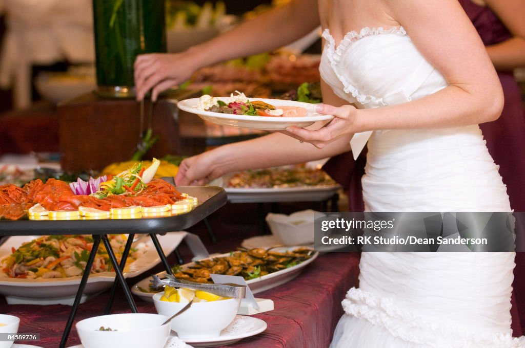Bride getting food from buffet.