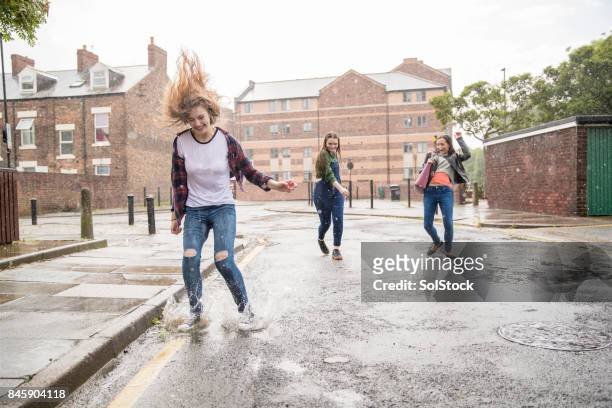 teens enjoying the rain - friend mischief stock pictures, royalty-free photos & images