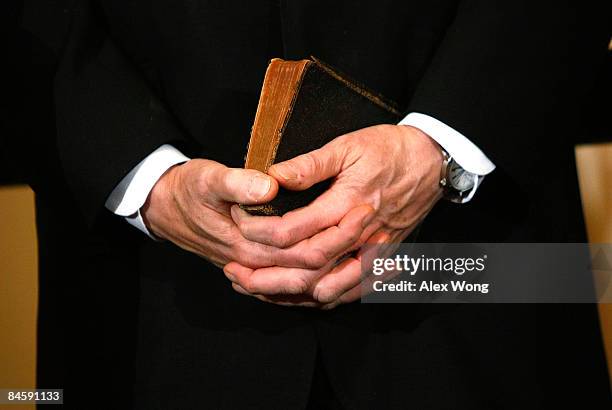 Former President Bill Clinton holds a bible during the ceremonial swearing-in for his wife Secretary of State Hillary Clinton at the State Department...