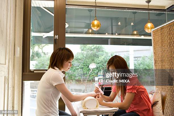 beautician filing nails - nail salon stock pictures, royalty-free photos & images