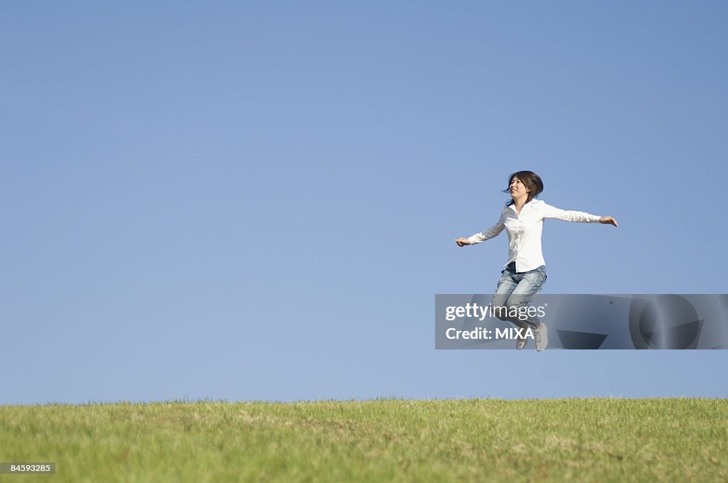 Young woman jumping on grass