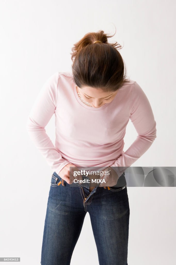 Mid adult woman putting on jeans