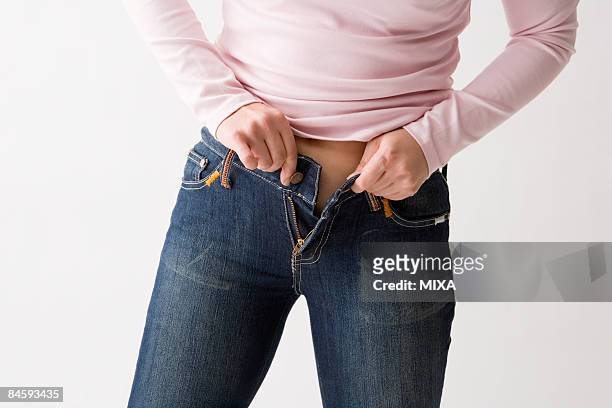 mid adult woman putting on jeans - too small stockfoto's en -beelden