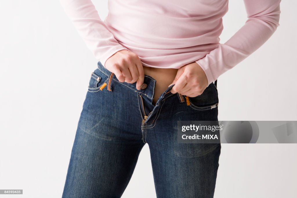 Mid adult woman putting on jeans