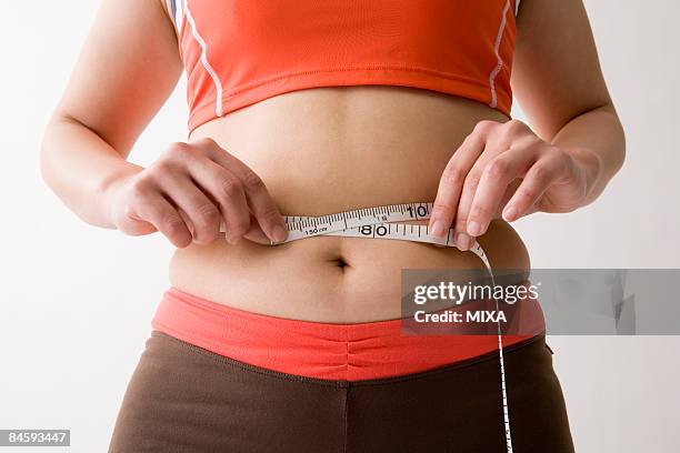 mid adult woman measuring her waist - measure waist stock pictures, royalty-free photos & images