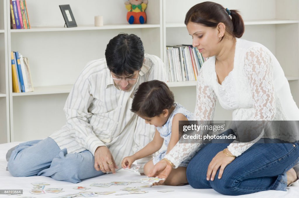 Mid adult couple with their daughter playing cards