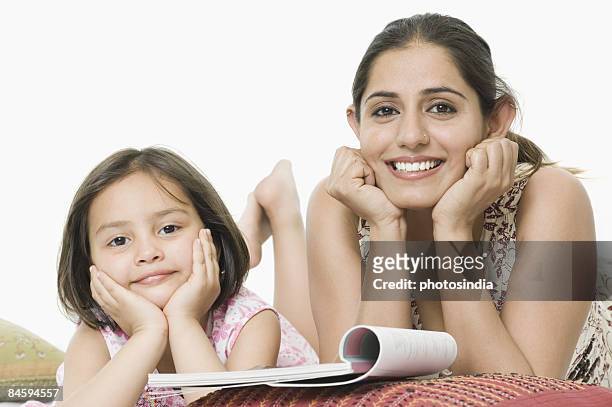 portrait of a young woman lying down with her daughter and smiling - child lying down stock pictures, royalty-free photos & images