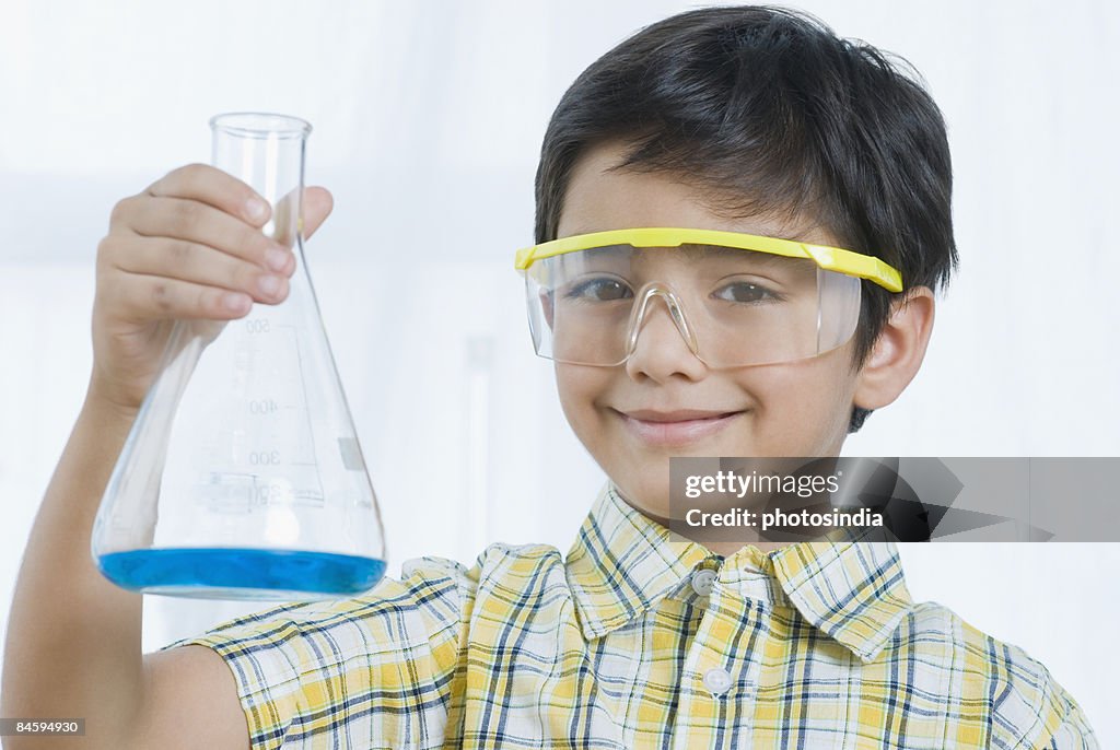 Portrait of a boy holding a conical flask and smiling