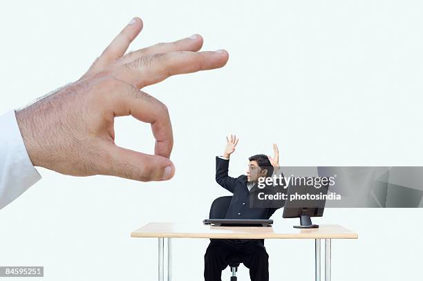 person's hand flicking a businessman sitting with his arms raised - dare un colpetto foto e immagini stock