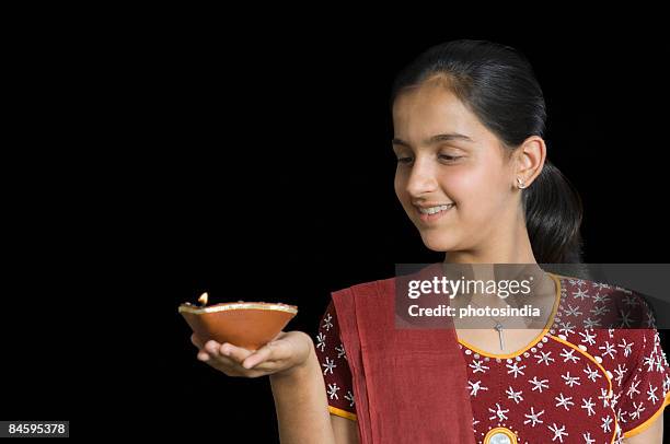 close-up of a teenage girl holding an oil lamp and smiling - diya oil lamp stockfoto's en -beelden