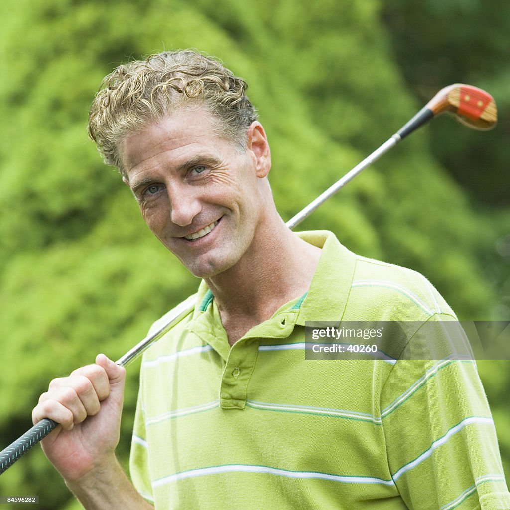 Portrait of a mature man holding a golf club and smiling
