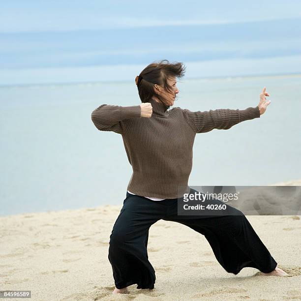 mature woman practicing martial arts on the beach - fighting stance stock pictures, royalty-free photos & images