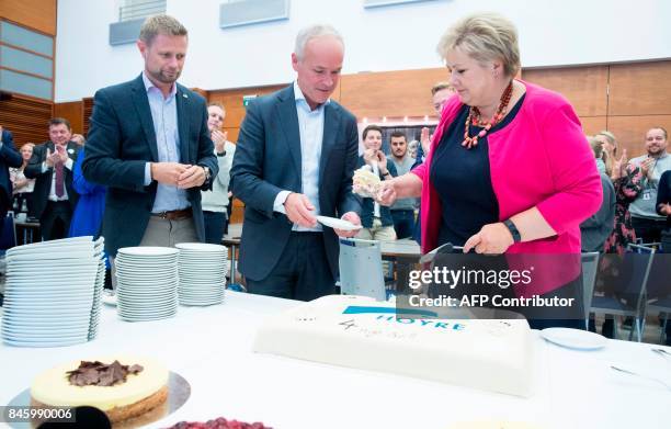 Norway's Prime Minister Erna Solberg distributes a cake on September 12, 2017 in Oslo to the Minister of Health and Care Services Bent Hoie and the...