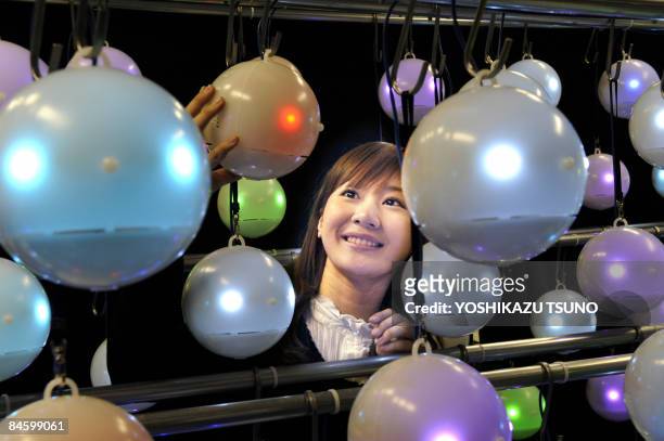 Employee for Japanese weather forecasting company Weathernews, Mayuka Nakatani, displays some of the 500 pod-shaped pollen counting robots called...