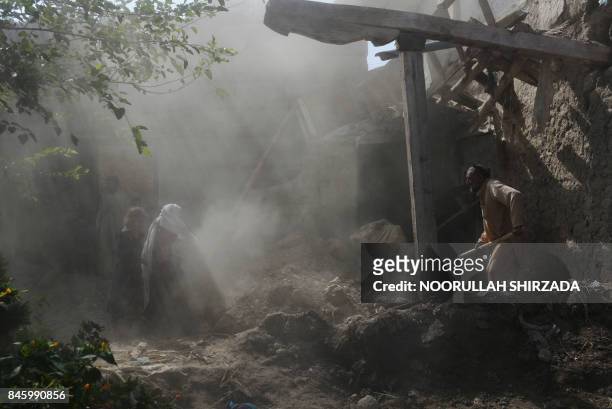 Afghan residents clear rubble from their homes after they were damaged by US airstrikes during ongoing clashes with Islamic State militants in the...