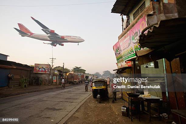 Man makes chapatis as an Air India passenger jet flies over the Jari Mari slum before landing at Mumbai Airport, on February 3, 2009 in Mumbai,...