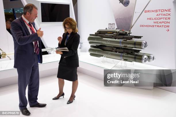 Delegates talk as they stand near a missile system on the "MBDA" display area at the DSEI event at the ExCel centre on September 12, 2017 in London,...