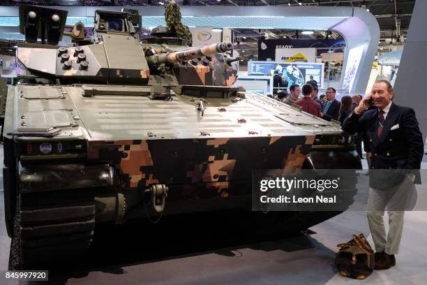Man chats on his phone as he leans on a CV90 Battle Station in the "BAE Systems" display area at the DSEI event at the ExCel centre on September 12,...
