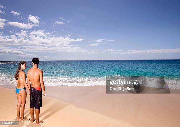 young couple holding hands standing on beach - sunset beach 個照片及圖片檔