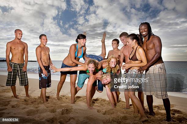 group of friends playing on beach, sunset - friend mischief stock pictures, royalty-free photos & images