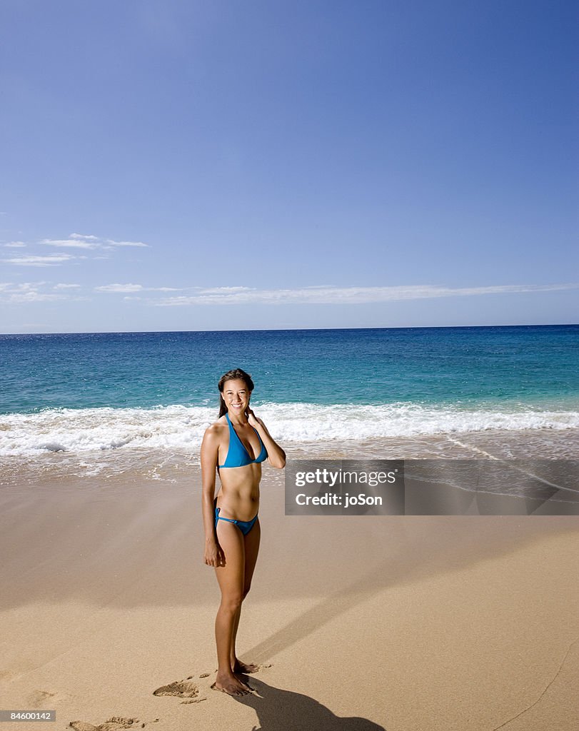 Young woman standing on beach, smile