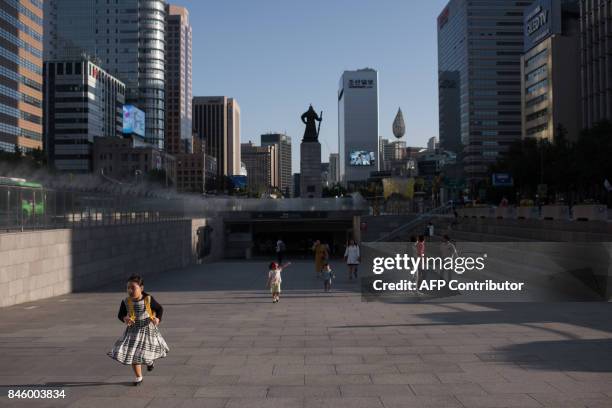 Child runs through Gwanghwamun plaza in central Seoul on September 12, 2017. / AFP PHOTO / Ed JONES