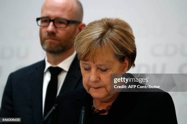 German Chancellor Angela Merkel stands next to CDU secretary general Peter Tauber as she gives a statement on September 12, 2017 in Berlin to express...