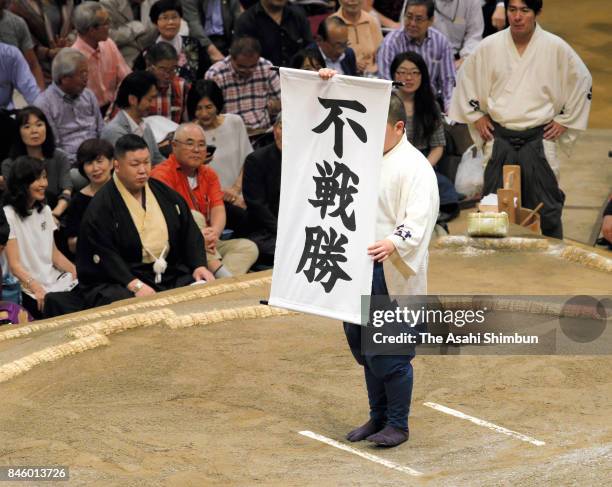 Staff holds a banner to announce Mongolian wrestler Ichinojo's win by default as Ura withdrew due to the injury during day three of the Grand Sumo...