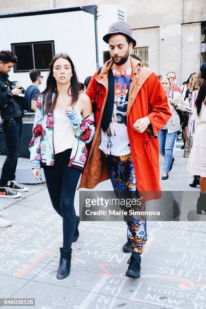 Guests are seen after Hakan Akkaya runway show wearing blue bomber jacket, blue printed panta and orange long coat during New York Fashion Week on...