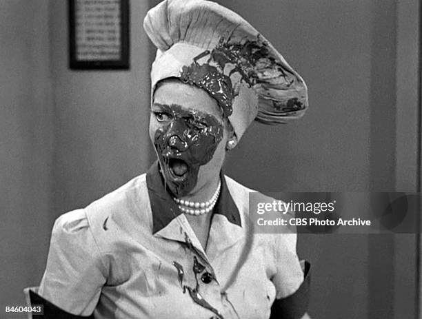 American comedienne and actress Lucille Ball , as Lucy Ricardo with a face covered in chocolate, works in a candy factory in an episode of the...