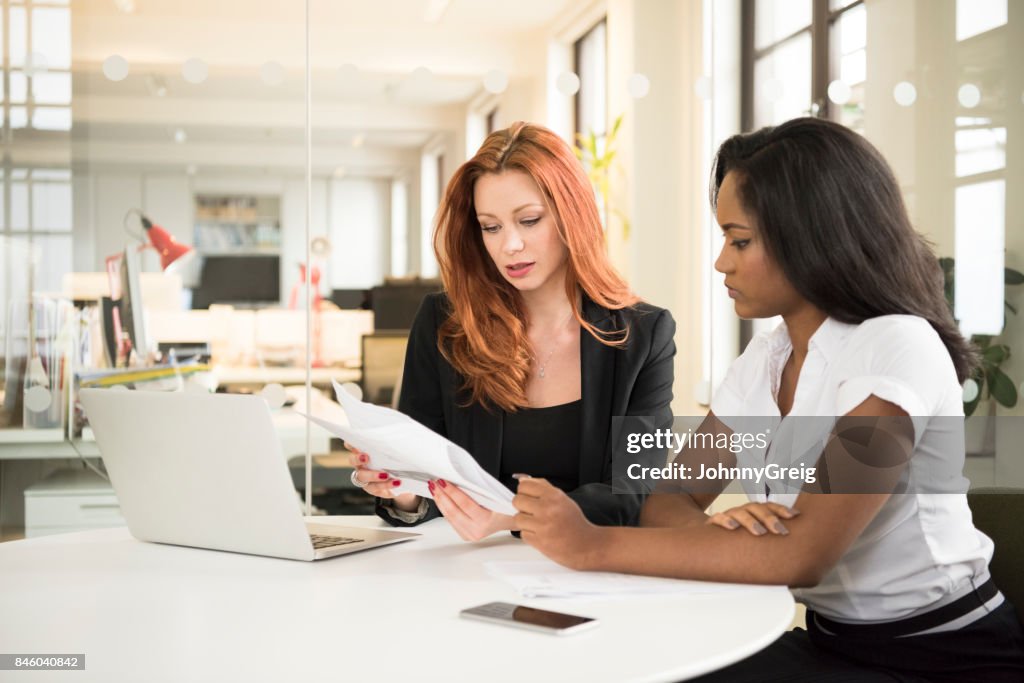 Female manager explaining documents to young businesswoman