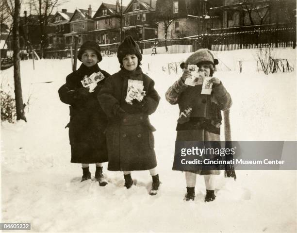 Three young children show off their Valentine's Day cards in while enjoying the outdoor snows on Hearne Avenue in the Avondale section of Cincinnati,...