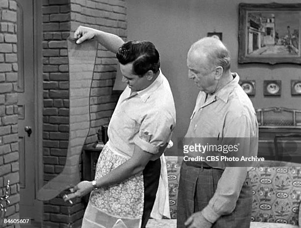 Watched by American actor William Frawley , Cuban-born American actor and musician Desi Arnaz holds up a woman's stocking, a cigarette in one hand,...