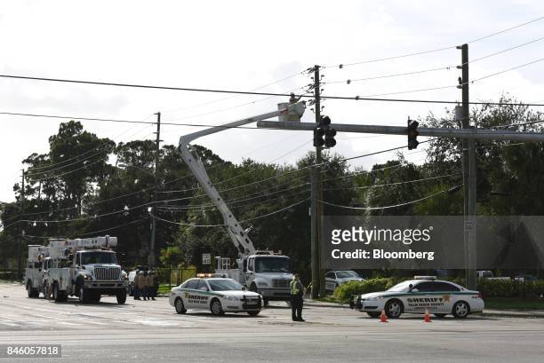 Florida Power & Light Co. Crews work on downed power lines from Hurricane Irma as Palm Beach County Sheriff officers block an intersection in West...