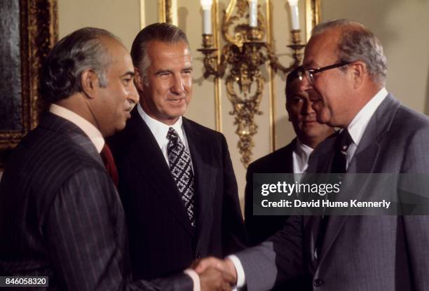 During a State visit, President of Pakistan Zulfikar Ali Bhutto shakes hands with US Secretary of the Treasury George P Shultz , watched by US Vice...