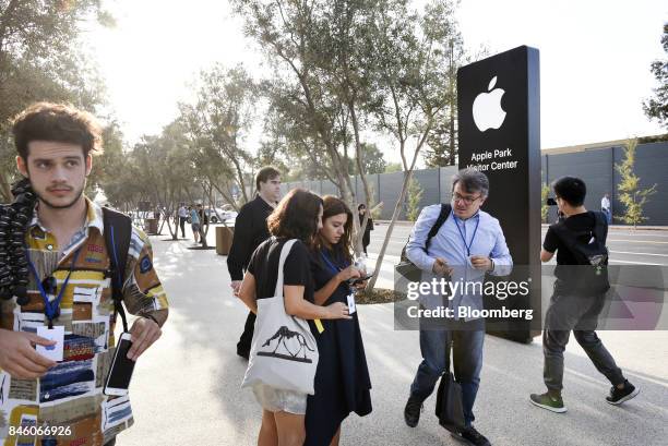 Attendees stand near Apple Inc. Signage ahead of an event at the Steve Jobs Theater in Cupertino, California, U.S., on Tuesday, Sept. 12, 2017. Apple...