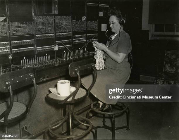 View of a multi-tasking switchboard operator, Cincinnati, Ohio, ca.1920s. She is doing lacework while handling the influx of phone calls to her...