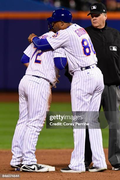 Phillip Evans of the New York Mets is hugged by first base coach Tom Goodwin after a double against the Cincinnati Reds during the fifth inning at...