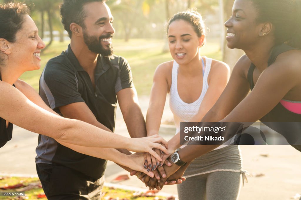 Glücklich multiethnischen sportliche Freunde Stapeln Hände im park