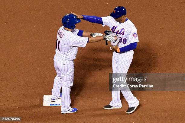 Norichika Aoki of the New York Mets is greeted by first base coach Tom Goodwin at second base against the Cincinnati Reds during the seventh inning...