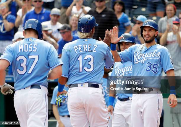 Eric Hosmer of the Kansas City Royals congratulates Salvador Perez and Brandon Moss as they cross the plate to score after Moss hit a grand slam home...