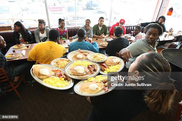 Denny's waitresses deliver free Grand Slam breakfasts to customers February 3, 2009 in Emeryville, California. People lined up at Denny's across...