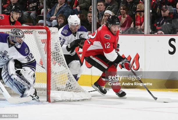 Mike Fisher of the Ottawa Senators stickhandles the puck from behind the net against Dustin Brown and Jonathan Quick of the Los Angeles Kings at...