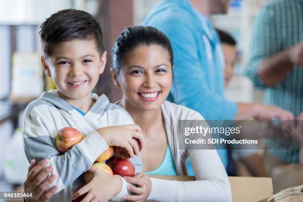 confident boy and his mom donate food to homeless shelter - recolha-de-alimentos imagens e fotografias de stock