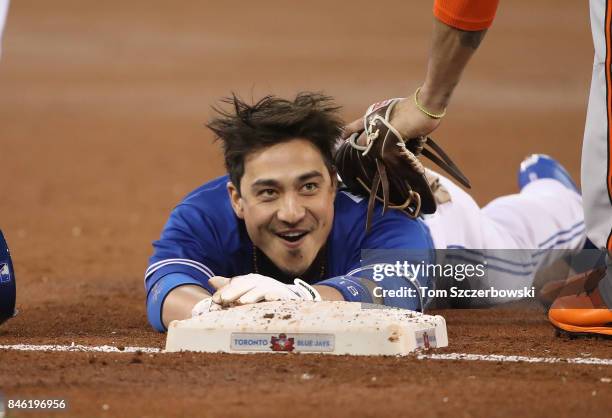 Darwin Barney of the Toronto Blue Jays laughs as he crawls into third base after stumbling in the second inning during MLB game action against the...