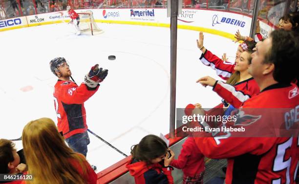 Mike Green of the Washington Capitals tosses a puck to the crowd before the game against the New Jersey Devils at Verizon Center on March 26, 2015 in...