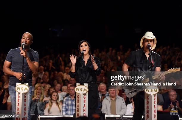 In this handout photo provided by Hand in Hand, Darius Rucker, Demi Lovato, and Brad Paisley perform onstage during Hand in Hand: A Benefit for...