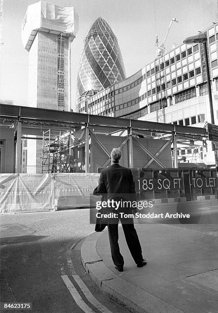 In the heart of London's financial district, a man stops to look at a construction site where new offices are being built in the shadow of the...