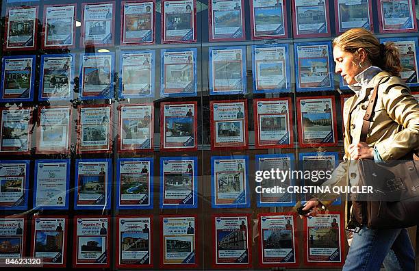 Woman walks by a real estate agency in Sevilla on February 4, 2009. Overwhelmed by a deepening economic contraction and a sharp rise in unemployment,...