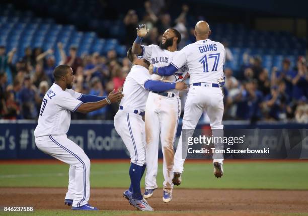 Richard Urena of the Toronto Blue Jays is congratulated by teammates after hitting the game-winning RBI single in the ninth inning during MLB game...